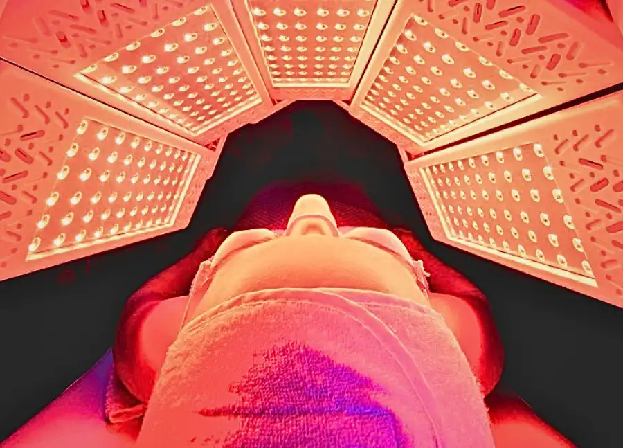 A woman inside of a red light bed